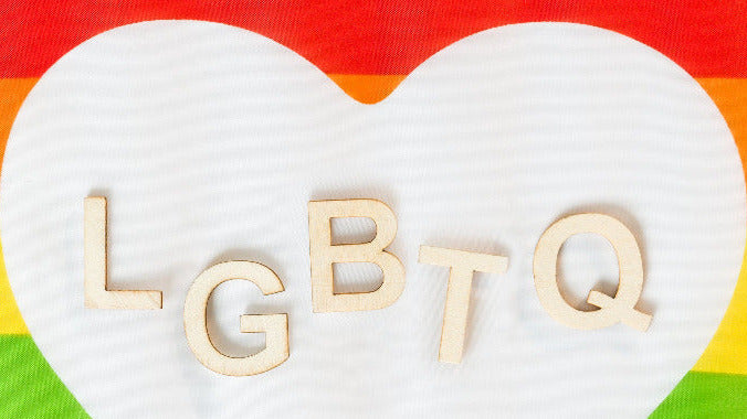 Heart-shaped object with 'LGBTQ' letters on a rainbow flag background